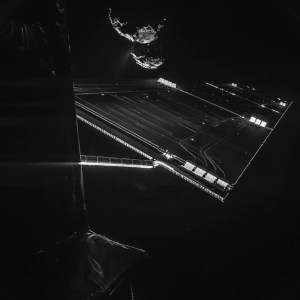 On Oct. 7, 2014, Comet 67P/C-G is framed by one of Rosetta’s solar wings, which is 46 feet long. A stream of gas and dust extends from an active area of the comet’s neck, about 10 miles away. Credit: ESA